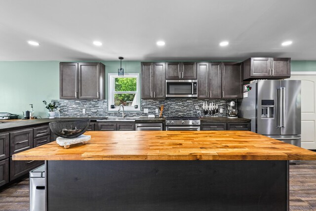kitchen featuring wood counters, premium appliances, dark wood-style floors, tasteful backsplash, and recessed lighting