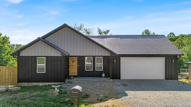 view of front of property featuring an attached garage, gravel driveway, and fence