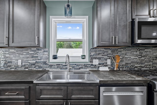 kitchen featuring appliances with stainless steel finishes, a sink, tasteful backsplash, dark brown cabinetry, and hanging light fixtures