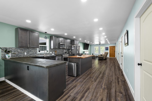 kitchen with stainless steel appliances, recessed lighting, tasteful backsplash, dark wood-style flooring, and a kitchen island