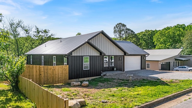 view of front of house with gravel driveway, a garage, fence, board and batten siding, and metal roof