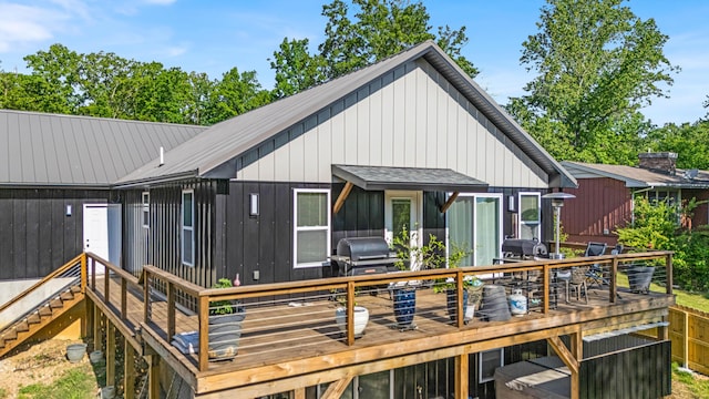 rear view of house featuring a wooden deck, outdoor dining area, and board and batten siding