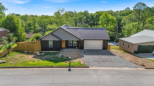 view of front of property with an attached garage, driveway, board and batten siding, and fence