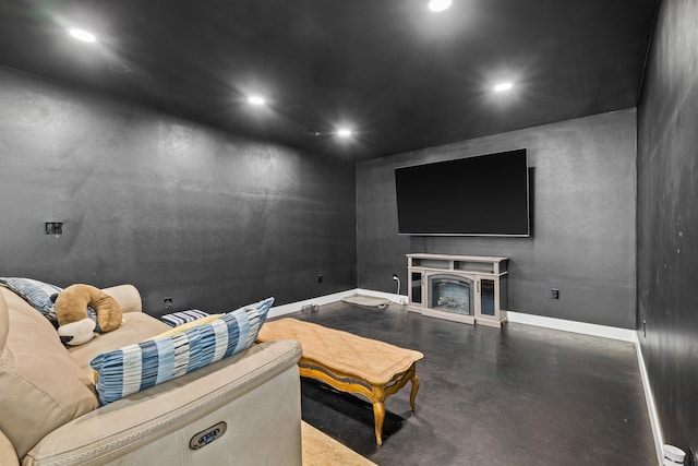 home theater room with finished concrete flooring, recessed lighting, baseboards, and a fireplace