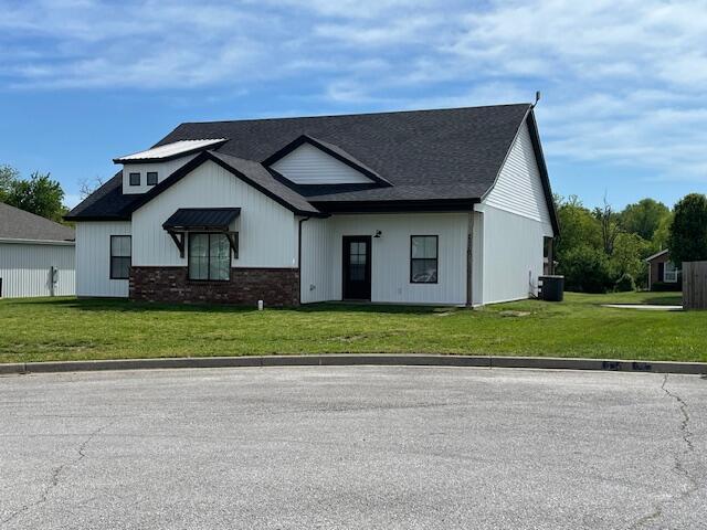 modern farmhouse style home with a front yard and central air condition unit