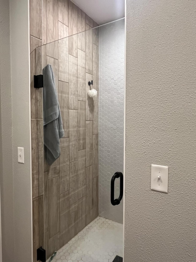 bathroom with a shower stall and a textured wall