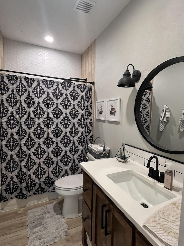 full bathroom featuring wood finished floors, toilet, vanity, backsplash, and a shower with curtain