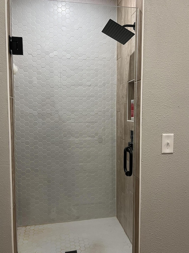 full bathroom featuring a stall shower and a textured wall