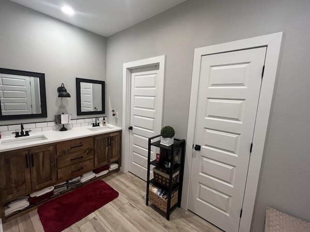 full bathroom featuring wood finished floors, backsplash, and double vanity