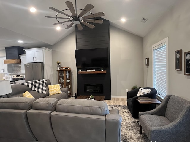living area with a ceiling fan, wood finished floors, lofted ceiling, a fireplace, and recessed lighting