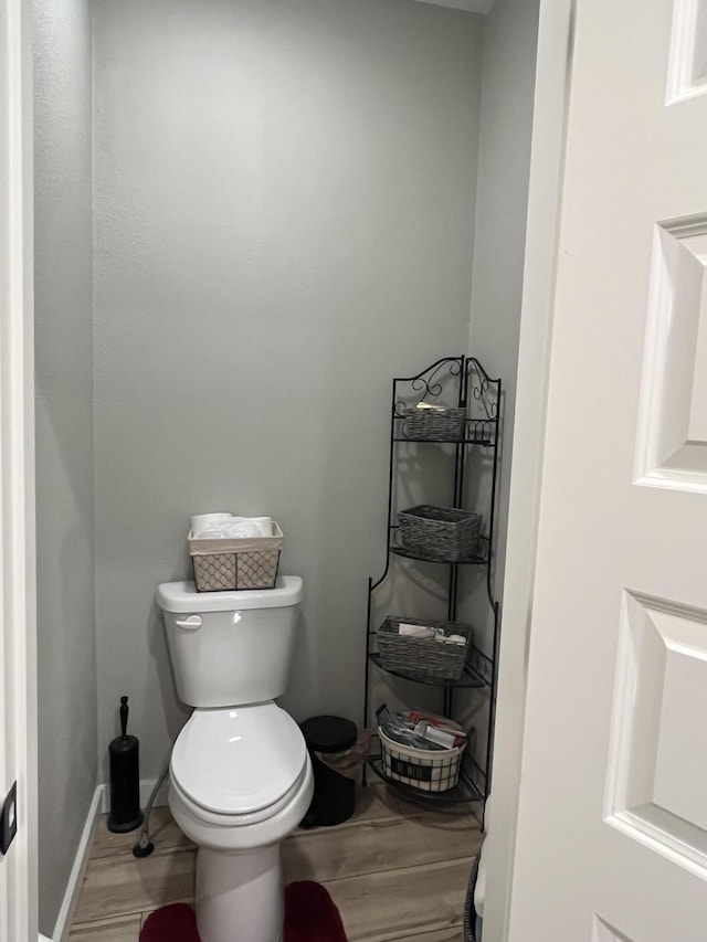 bathroom with wood finished floors, toilet, and baseboards