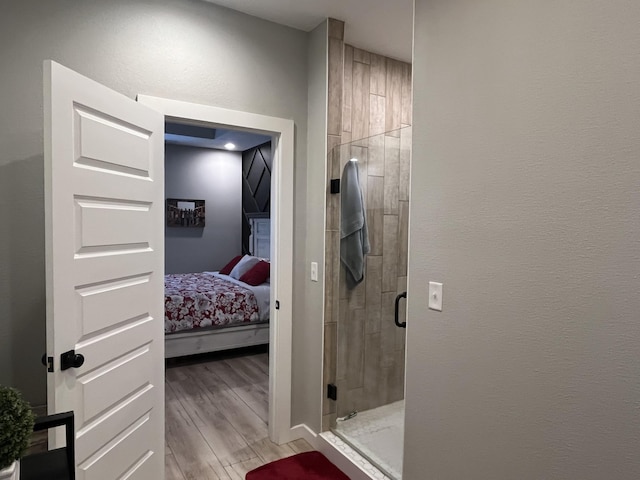 ensuite bathroom with a stall shower and wood finished floors