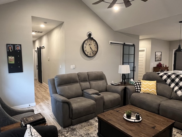 living area featuring a barn door, light wood-style floors, a ceiling fan, baseboards, and high vaulted ceiling