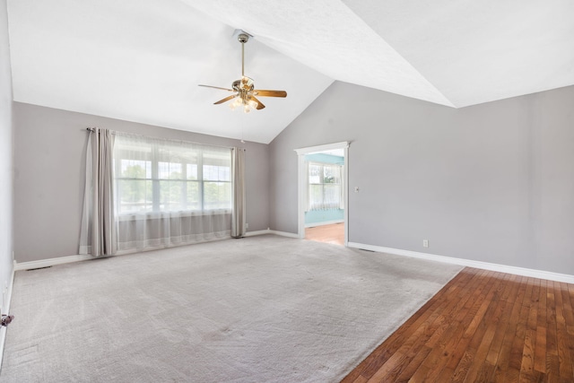 empty room featuring a ceiling fan, baseboards, high vaulted ceiling, and wood finished floors