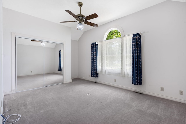 unfurnished bedroom featuring carpet flooring, lofted ceiling, a closet, ceiling fan, and baseboards