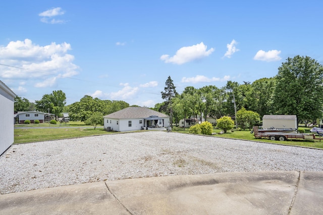 view of front of house with driveway, a front lawn, and view of scattered trees