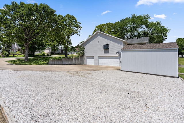 view of home's exterior featuring concrete driveway, a garage, and a shingled roof