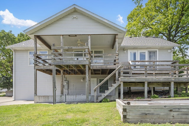 rear view of property featuring roof with shingles, a deck, a yard, and stairway