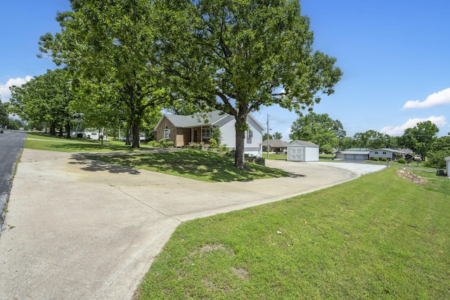 view of front of home featuring driveway, a front yard, a shed, and an outbuilding