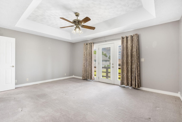 unfurnished room with a raised ceiling, baseboards, carpet flooring, french doors, and ceiling fan