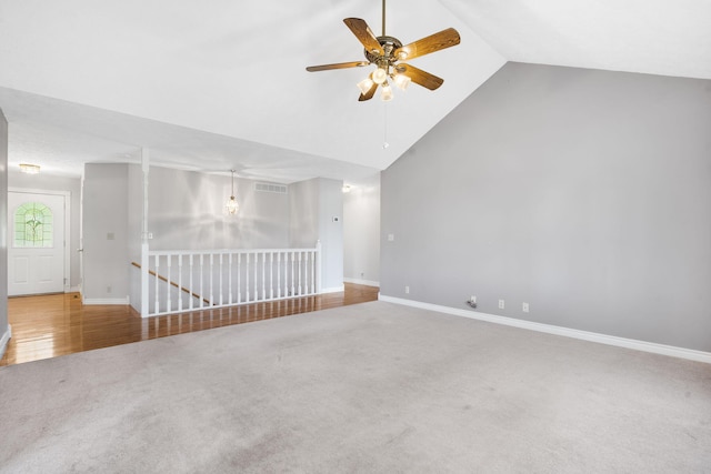 carpeted empty room with a ceiling fan, baseboards, and high vaulted ceiling