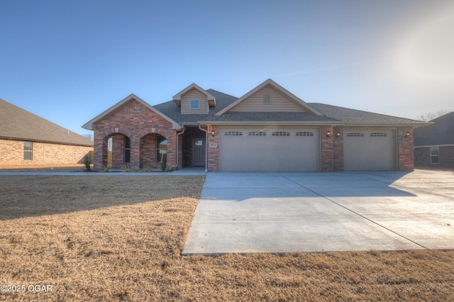 view of front facade with brick siding, a garage, concrete driveway, a front yard, and a shingled roof
