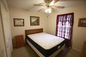 carpeted bedroom featuring a closet, baseboards, and a ceiling fan