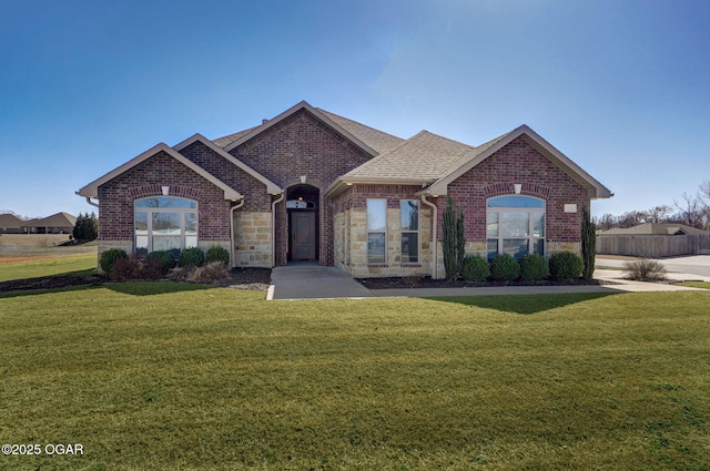 view of front of home with brick siding, a front lawn, and roof with shingles