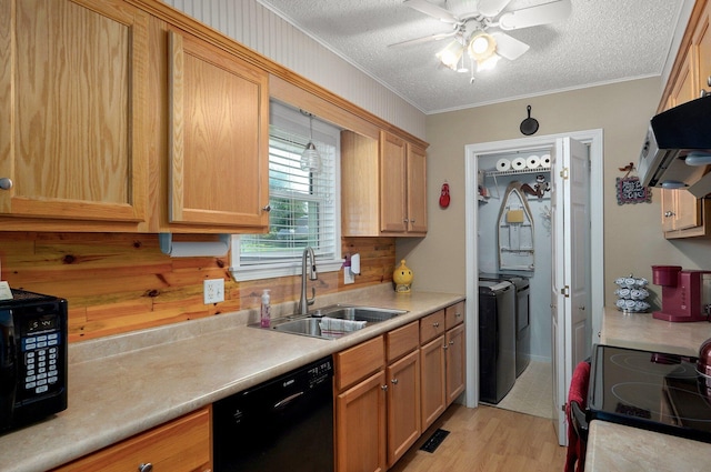 kitchen featuring black appliances, a sink, range hood, light countertops, and washing machine and clothes dryer