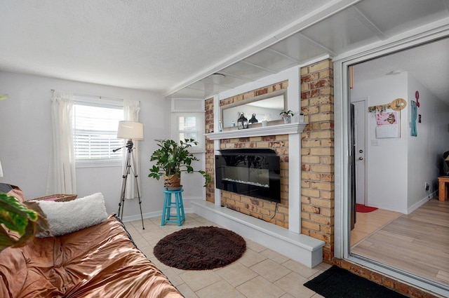 living area featuring a fireplace, a textured ceiling, light tile patterned floors, and baseboards