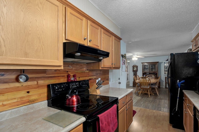 kitchen featuring black appliances, under cabinet range hood, ceiling fan, light countertops, and a textured ceiling