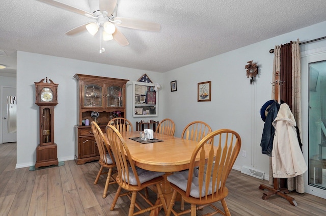 dining area featuring a textured ceiling, light wood-style flooring, and a ceiling fan