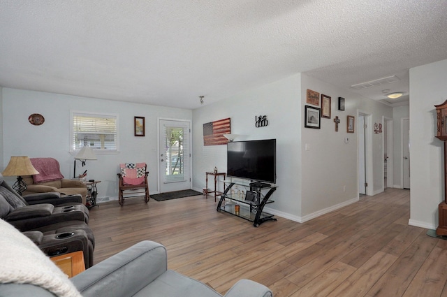 living area featuring light wood-style flooring, baseboards, and a textured ceiling