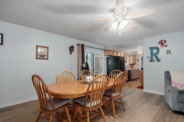 dining space with a textured ceiling, light wood-type flooring, ceiling fan, and baseboards