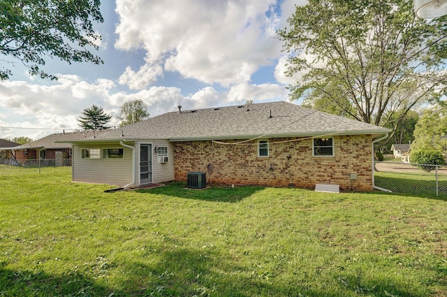 back of property with central AC, a shingled roof, and brick siding