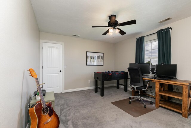 carpeted office space featuring a ceiling fan and baseboards