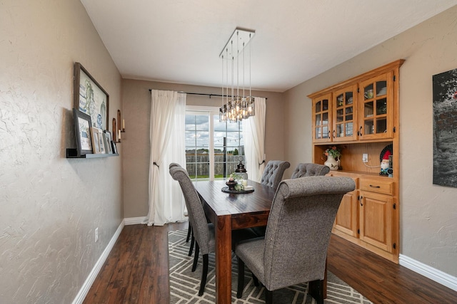 dining room with a textured wall, baseboards, dark wood-style floors, and a chandelier