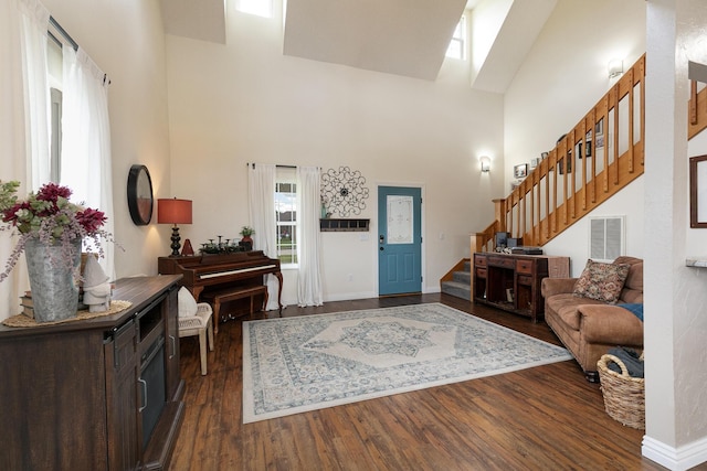 foyer entrance with a towering ceiling, stairway, dark wood-style floors, and baseboards