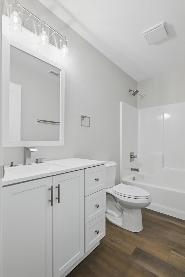 bathroom featuring toilet, vanity, wood finished floors, and tub / shower combination