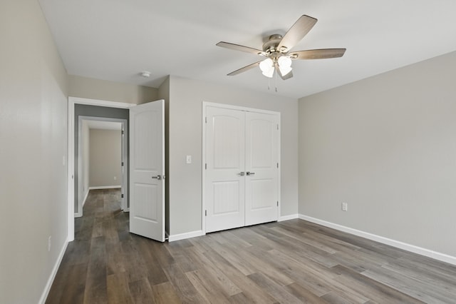 unfurnished bedroom with wood finished floors, baseboards, a closet, and a ceiling fan