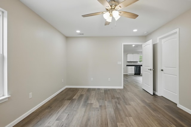 spare room with wood finished floors, a ceiling fan, recessed lighting, and baseboards