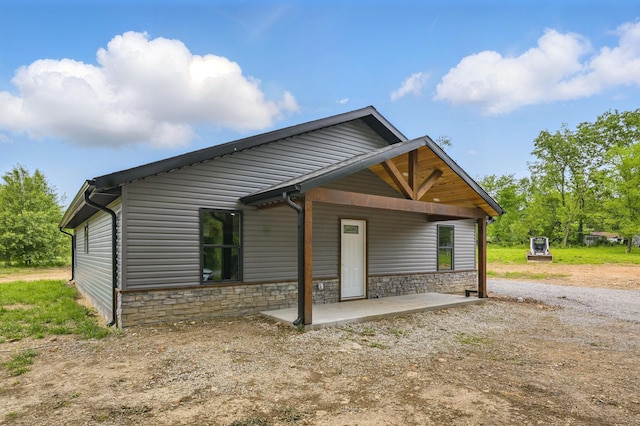view of front facade with a patio and stone siding