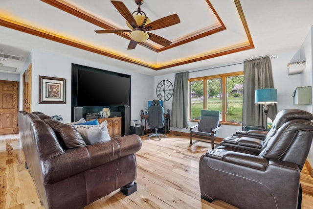 living room featuring a tray ceiling, ceiling fan, and light wood-style flooring