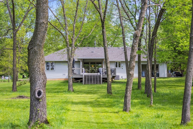 view of front of house featuring a wooden deck, a front yard, and roof with shingles