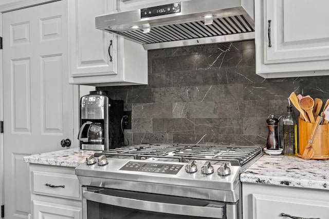 kitchen featuring gas range, extractor fan, tasteful backsplash, white cabinetry, and light stone countertops