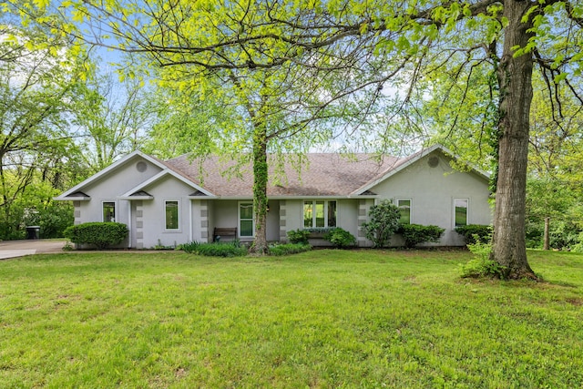 ranch-style house featuring stucco siding, a front yard, and a shingled roof