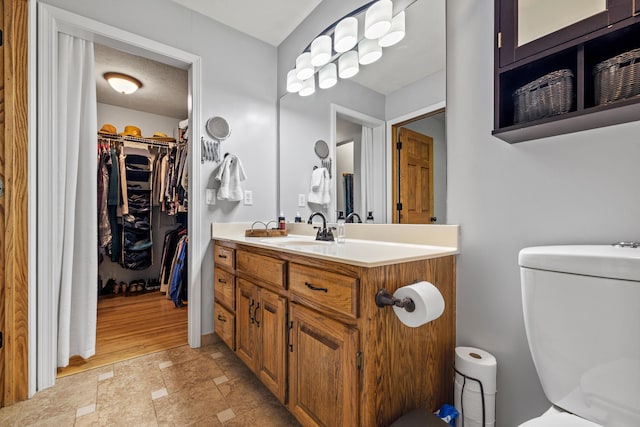 bathroom with toilet, vanity, and a spacious closet