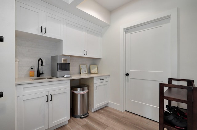 kitchen with a sink, decorative backsplash, light wood finished floors, and light countertops