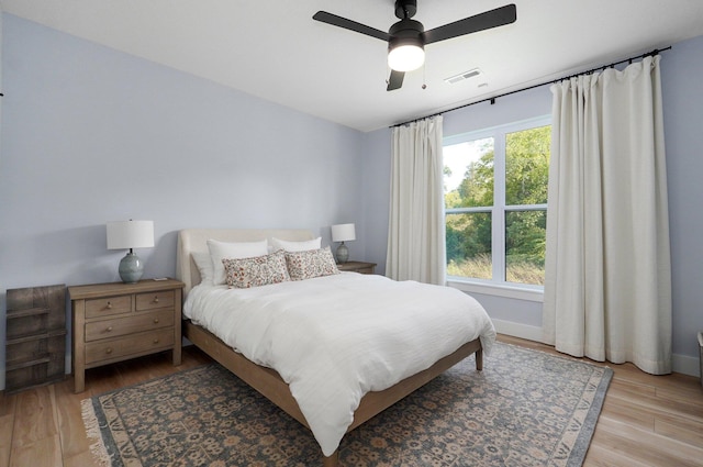 bedroom featuring light wood-type flooring, a ceiling fan, and baseboards