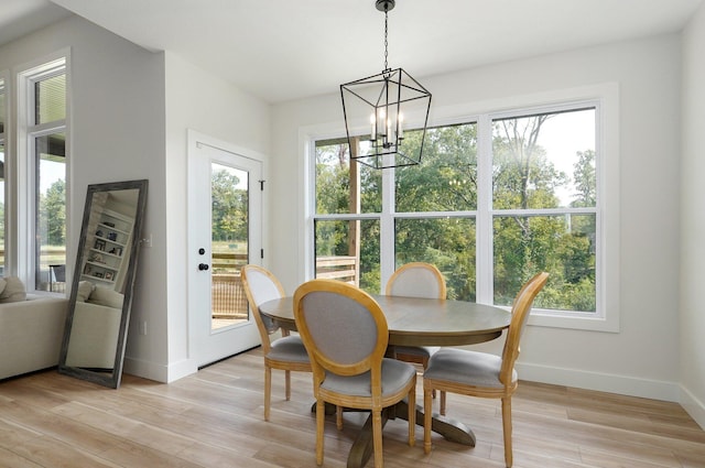 dining area with a chandelier, baseboards, and light wood-style flooring